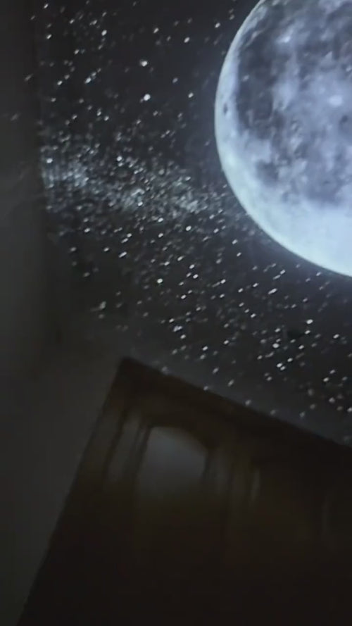 Galaxy Star Projector projecting a full moon and stars on a bedroom ceiling